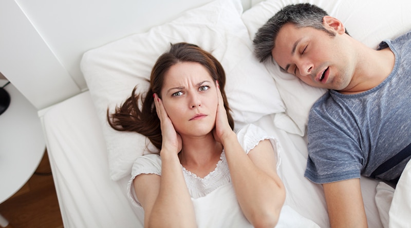 Woman covering ears, annoyed by husband's sleep apnea