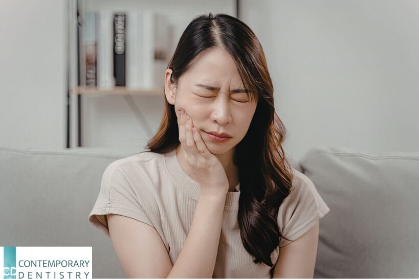 Woman experiencing jaw pain, holding her cheek with eyes closed, illustrating TMJ or TMD symptoms such as facial discomfort and jaw soreness.